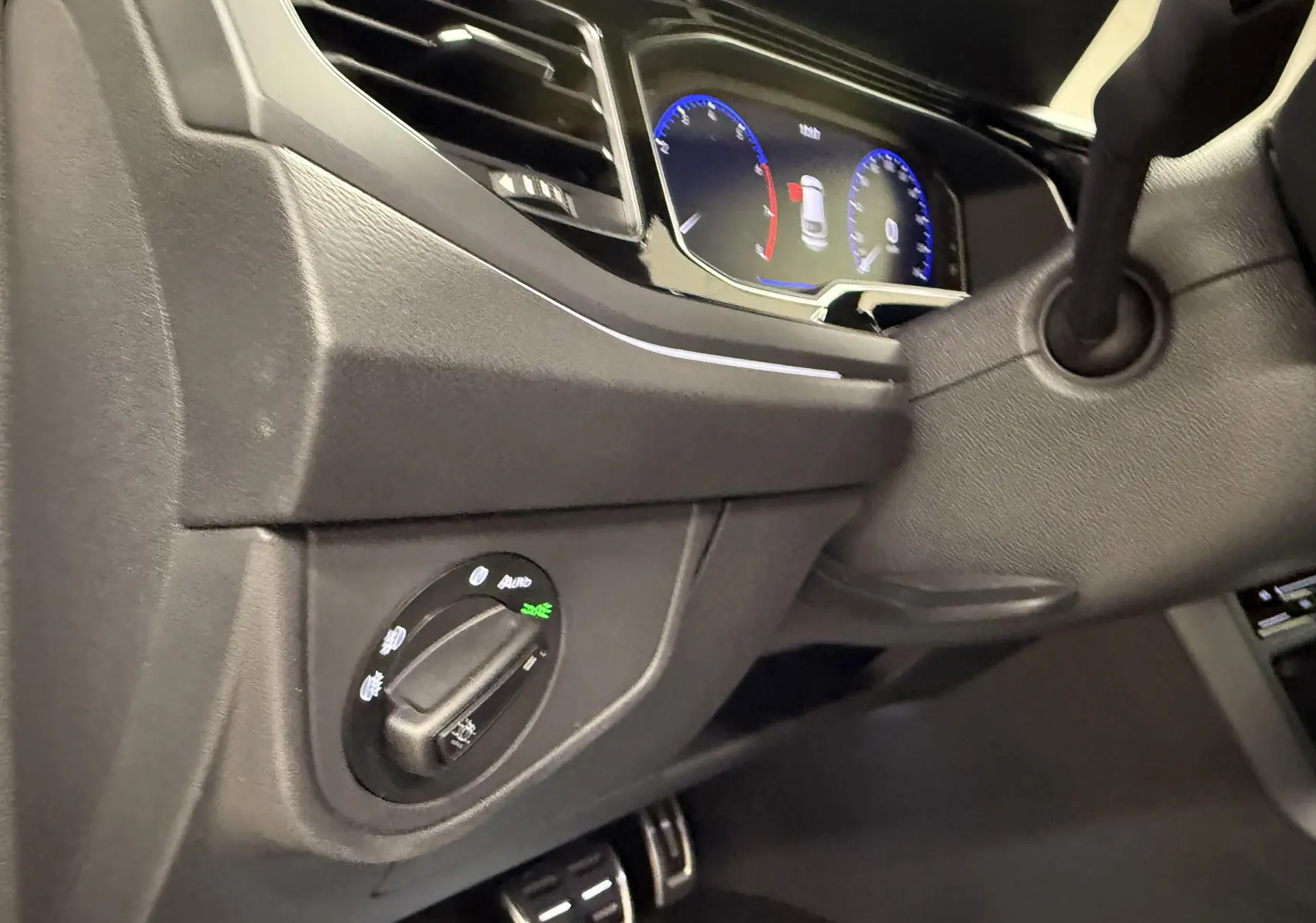 Vue intérieure côté gauche du tableau de bord gris foncé du Volkswagen Taigo avec commandes d'éclairage et combiné d'instruments digital.