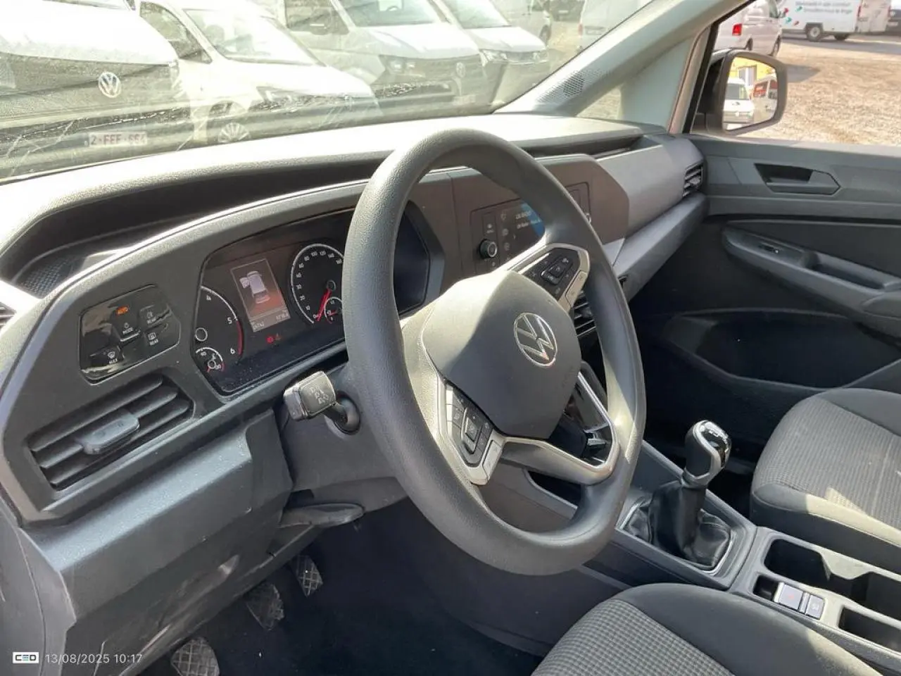 Intérieur de Volkswagen Caddy blanc Candy 2024, vue côté conducteur sur le volant multifonctions et la boîte manuelle.