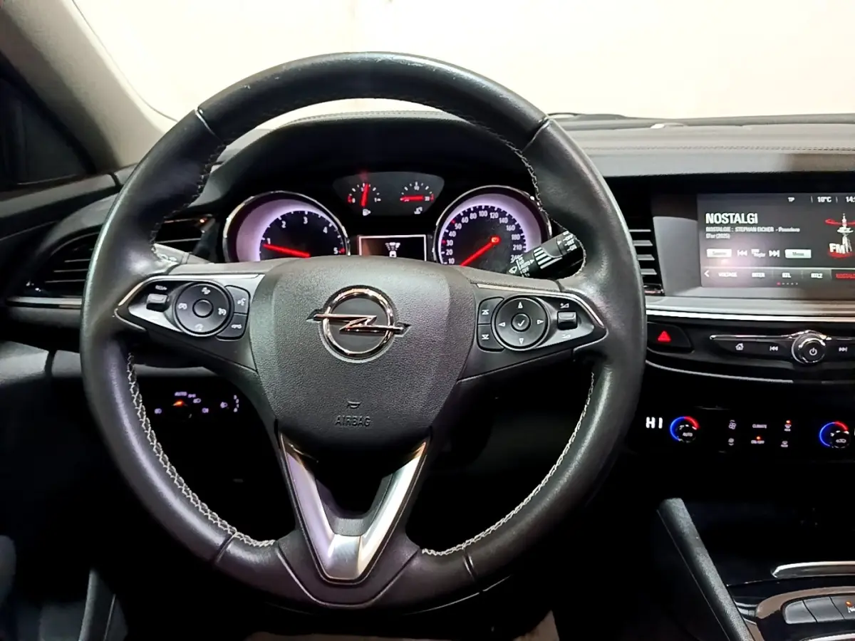 Vue intérieure centrée sur le volant cuir multifonctions et le tableau de bord avec écran tactile de l’Opel Insignia rouge.