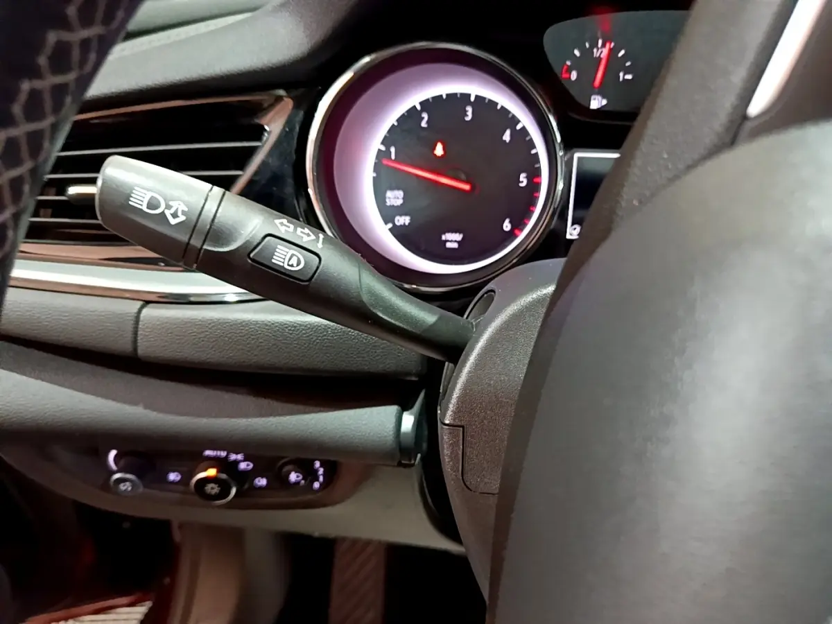 Gros plan sur la commande des phares et clignotants à gauche du volant de l’Opel Insignia, tableau de bord en arrière-plan.