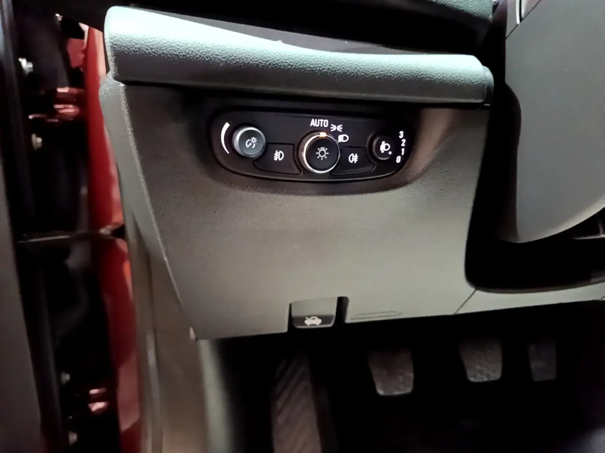 Détail du panneau de commande des phares côté gauche dans l’habitacle d’une Opel Insignia rouge de 2019.