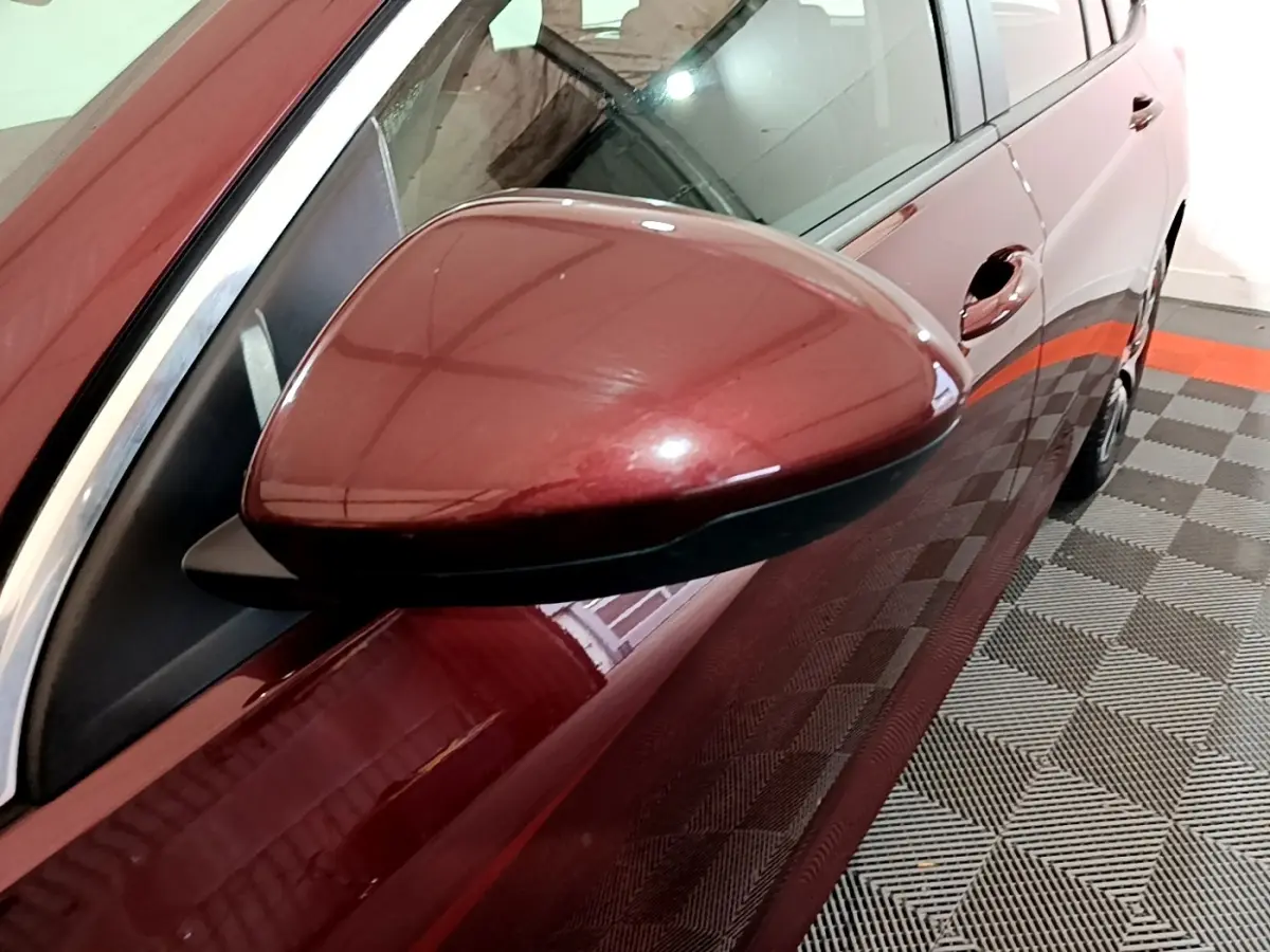 Rétroviseur côté gauche en gros plan sur Opel Insignia rouge, vue partielle du flanc et poignée de porte.