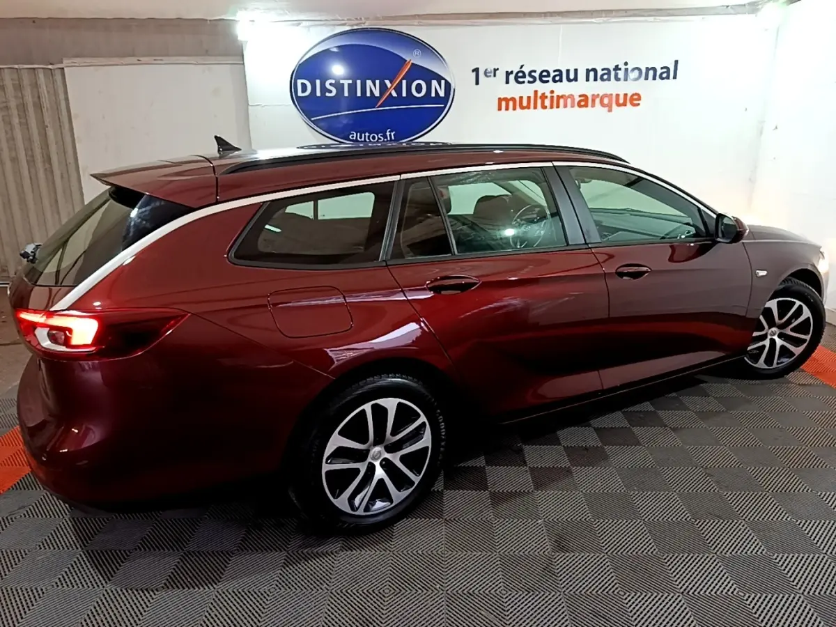 Opel Insignia rouge vue de profil droit en break, avec jantes alliage et feux arrière allumés.