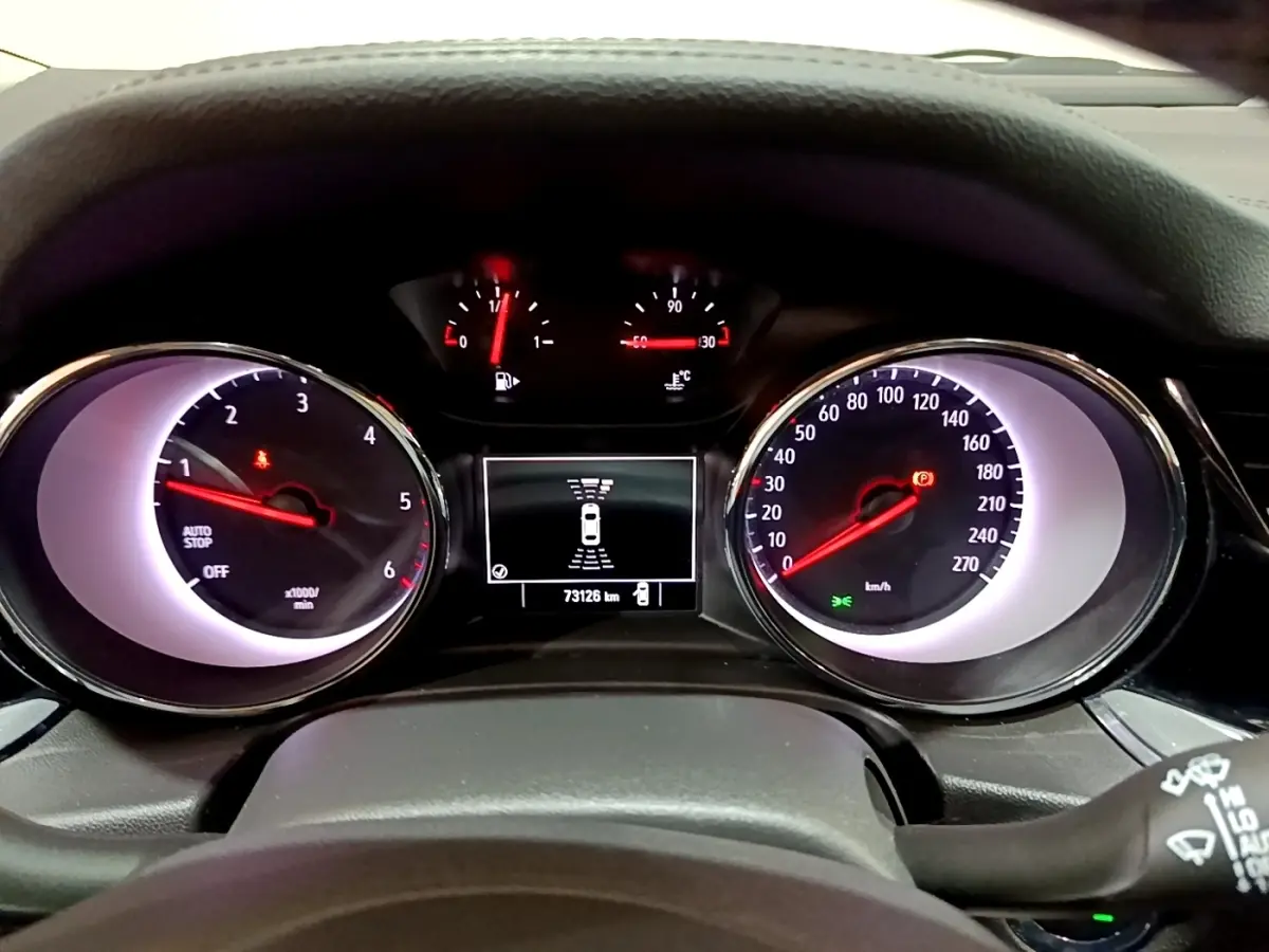 Vue rapprochée du tableau de bord de l'Opel Insignia rouge, affichant compte-tours, vitesse et écran central numérique.