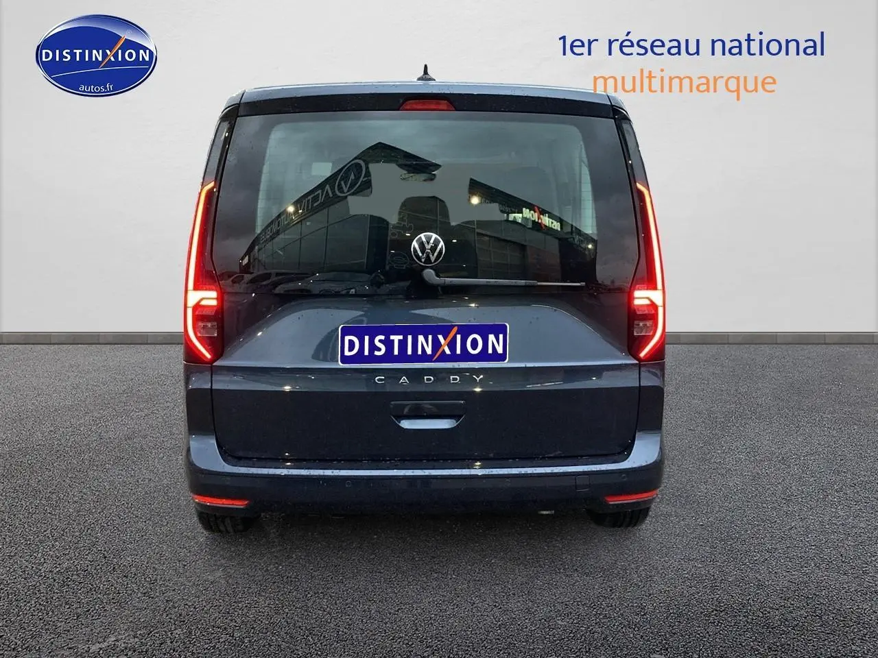 Vue arrière d'un Volkswagen Caddy bleu métallisé 2025 avec feux allumés et logo visible sur fond neutre.