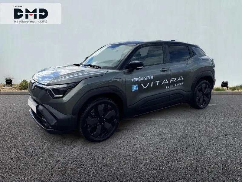 Vue 3/4 avant droite du Suzuki Vitara électrique 2026 en vert Land Breeze avec toit noir et jantes noires.