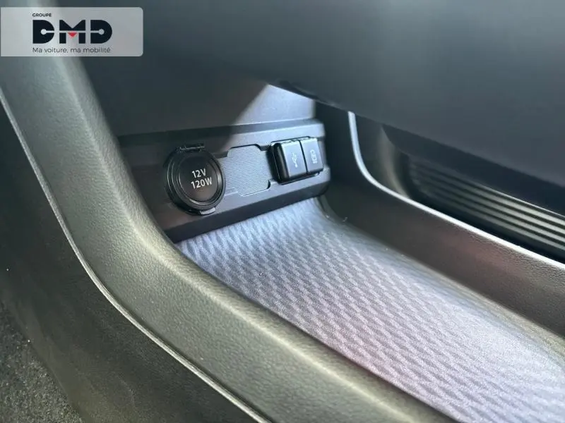 Gros plan sur la prise 12V et ports USB dans l'espace de rangement côté passager du Suzuki Vitara vert et toit noir.