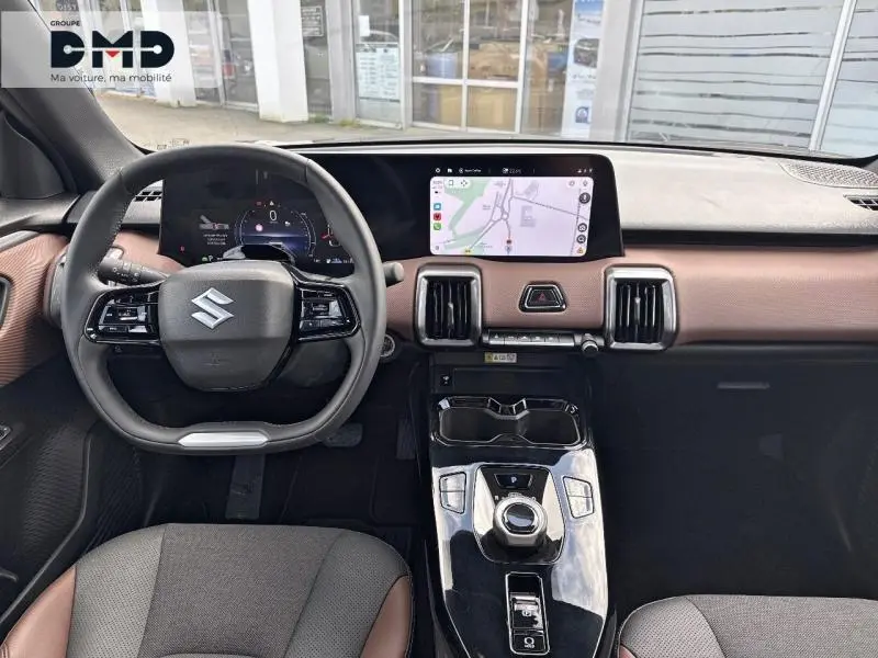 Vue intérieure frontale du Suzuki Vitara 2026 avec tableau de bord marron, écran tactile GPS et volant multifonction noir.