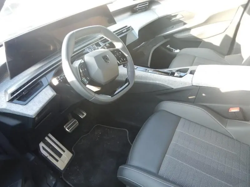 Vue intérieure côté conducteur du Peugeot 5008 gris 2025, avec volant compact, tableau de bord moderne et sièges tissu noir.