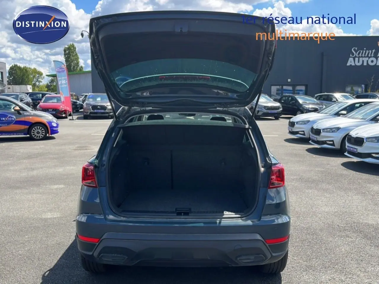 Vue arrière d'un SEAT Arona bleu Fjord avec coffre ouvert, montrant l'espace de chargement vide en extérieur.