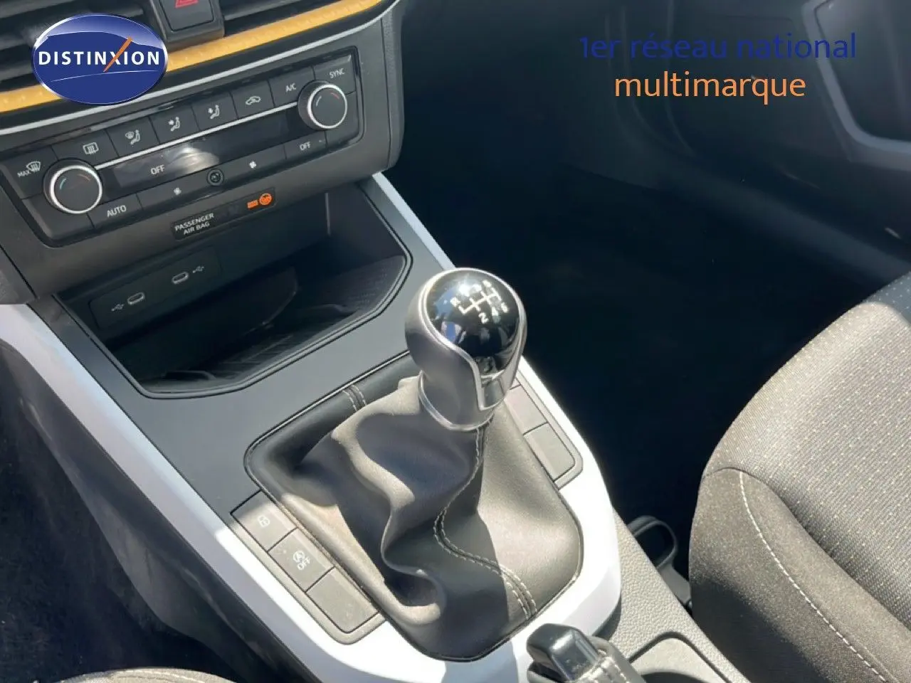 Gros plan sur la console centrale de la SEAT Arona 2025, boîte manuelle avec levier en cuir noir et tableau de bord gris.