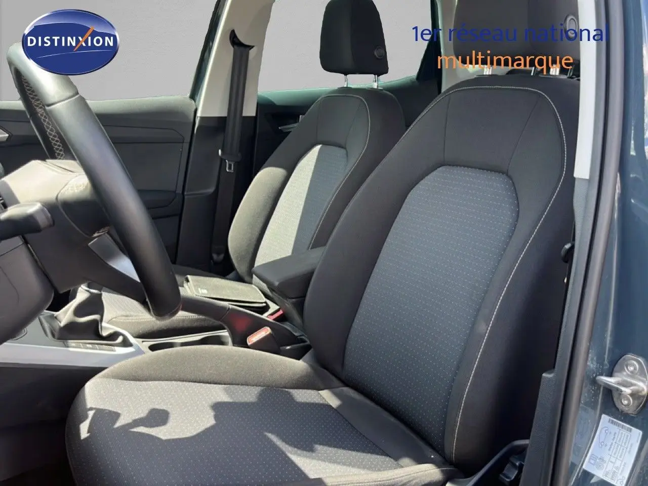 Vue intérieure côté conducteur du SEAT Arona 2025 bleu Fjord, montrant les sièges tissu gris-noir et la boîte manuelle.