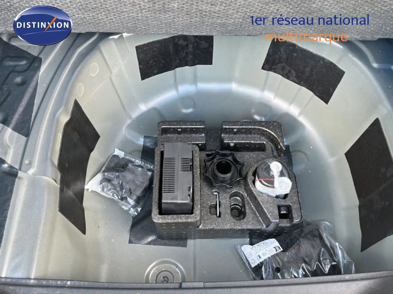 Coffre ouvert montrant la roue de secours et les outils de bord du SEAT Arona bleu Fjord avec toit blanc, vue de dessus.