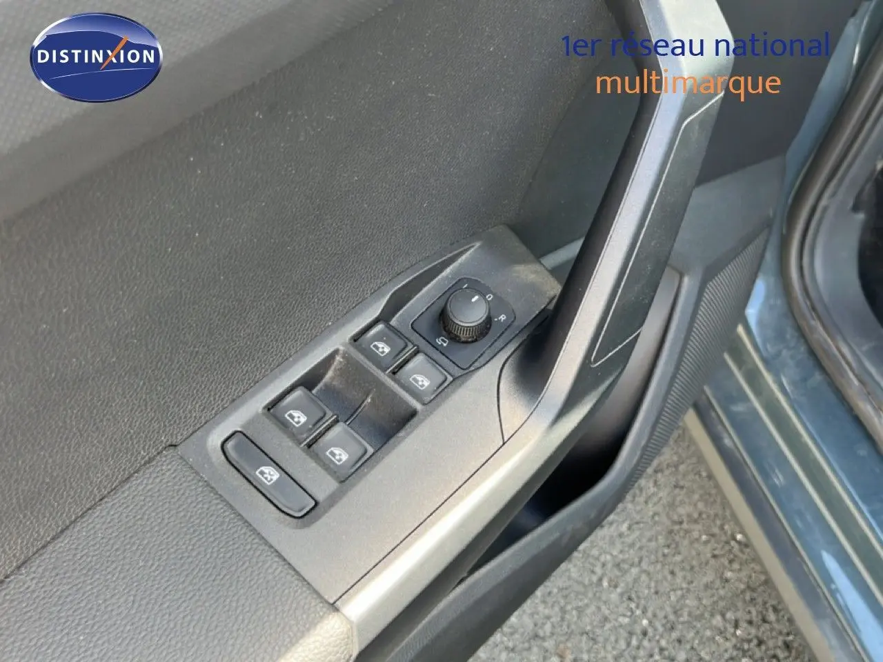 Gros plan sur les commandes des vitres et rétroviseurs côté conducteur d'une SEAT Arona bleu Fjord 2025.