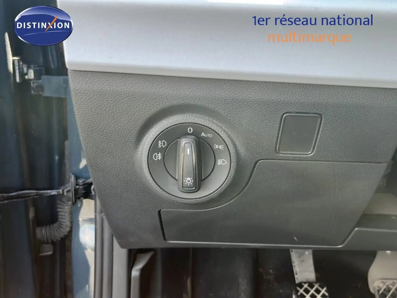 Gros plan sur le bouton de commande des phares côté gauche dans un SEAT Arona bleu Fjord avec toit blanc.