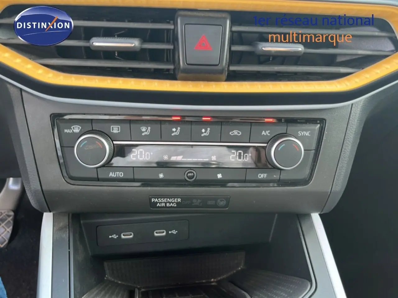Vue rapprochée de la console centrale du SEAT Arona 2025, avec climatisation digitale et bordure jaune vif.