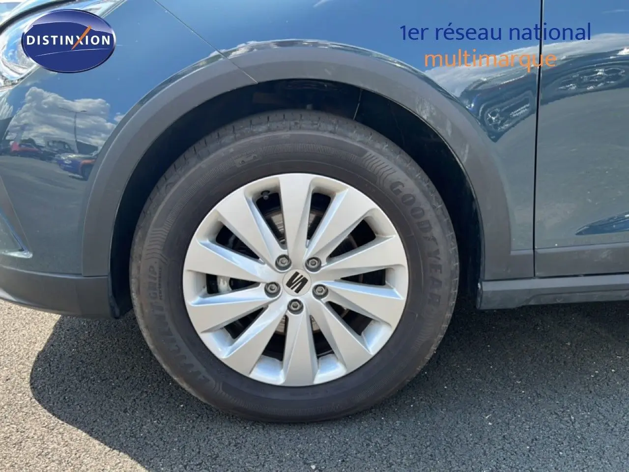 Gros plan sur la roue avant gauche d'un SEAT Arona bleu Fjord avec jante alliage et logo central SEAT.