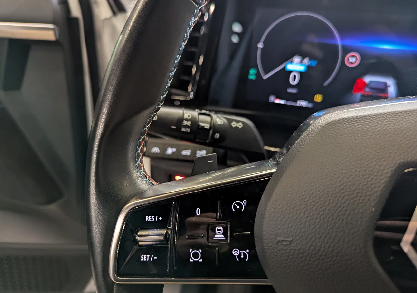 Gros plan sur le volant cuir noir du Renault Austral 2023 avec commandes de régulateur et tableau de bord numérique.