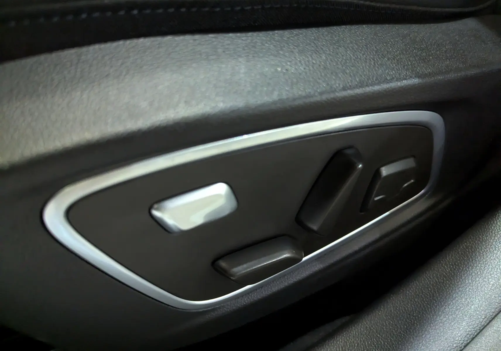 Commandes électriques des réglages de siège en gros plan sur une Renault Austral E-Tech blanc nacré, intérieur noir.