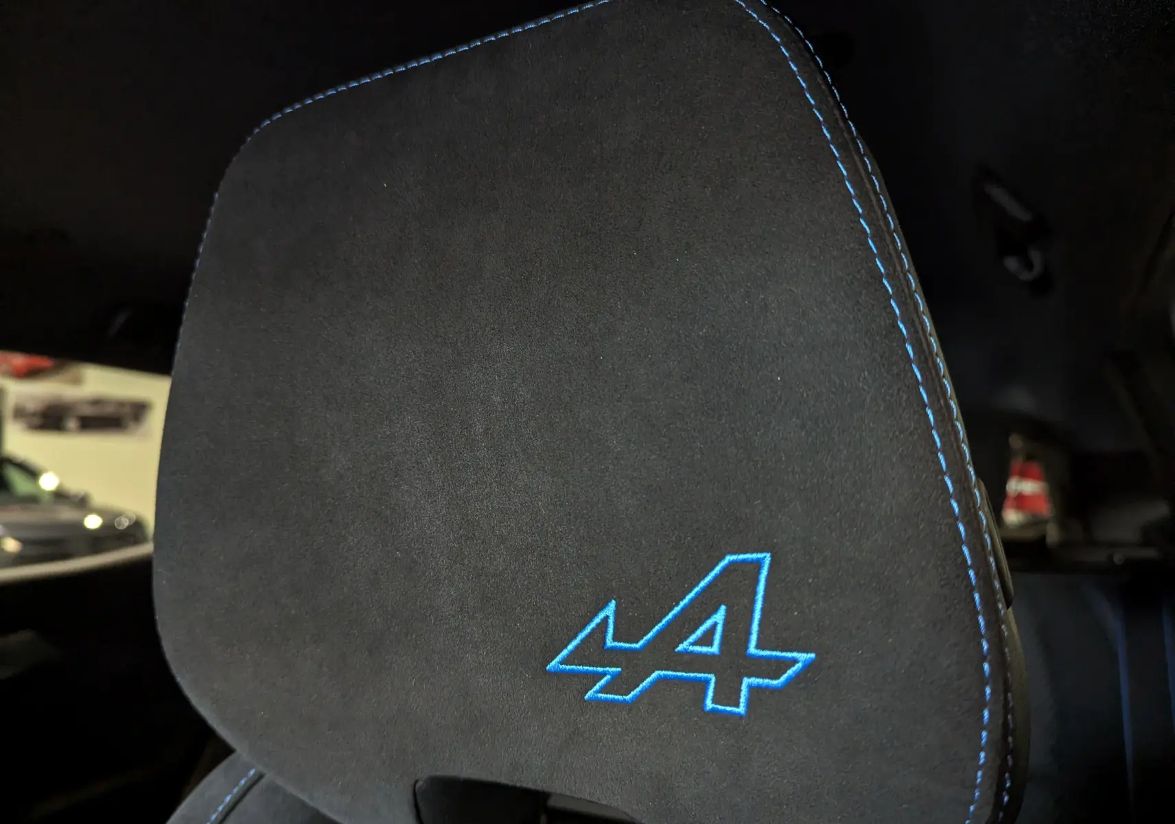 Gros plan sur l'appui-tête noir avec surpiqûres bleues et logo Alpine bleu du Renault Austral E-Tech 2023.