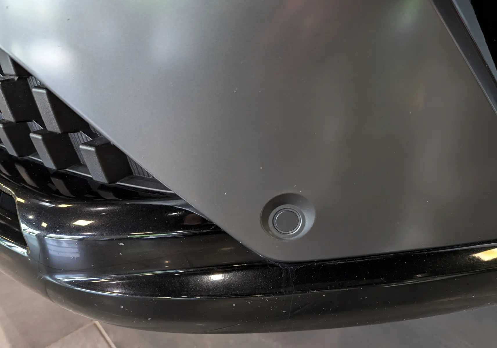 Détail du capteur de stationnement avant sur le pare-chocs noir du Renault Austral blanc nacré.