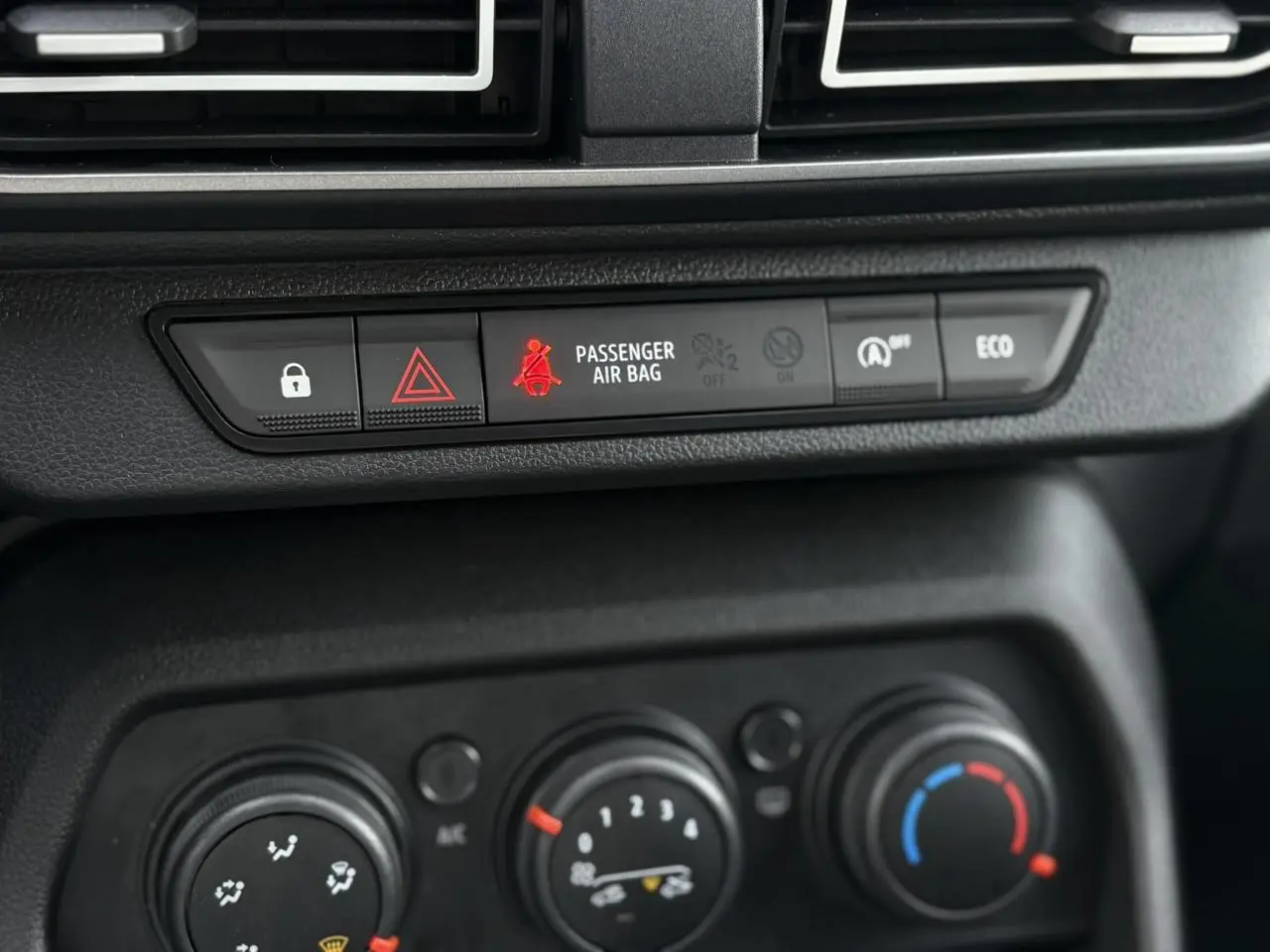 Gros plan sur la console centrale du Dacia Jogger 2024, montrant les commandes de climatisation et les boutons d'alerte et d'économie d'énergie.