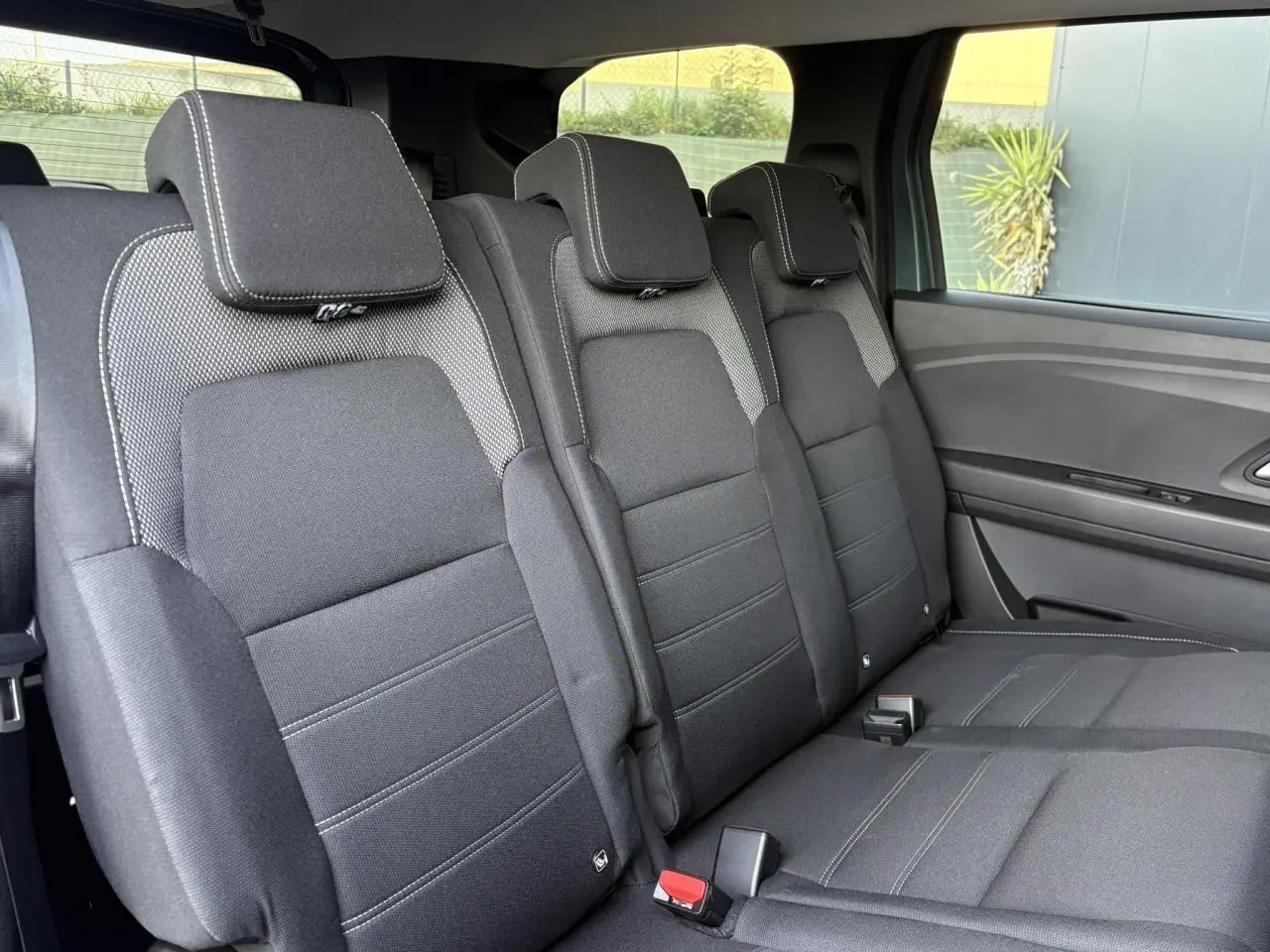 Banquette arrière en tissu gris foncé du Dacia Jogger 2024, vue côté droit avec trois appuie-têtes et ceinture de sécurité.