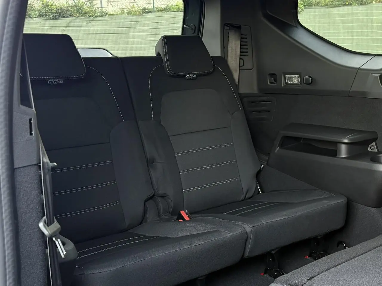 Banquette arrière rabattable noire du Dacia Jogger 2024 vue de côté droit, avec ceinture de sécurité et accoudoir intégré.