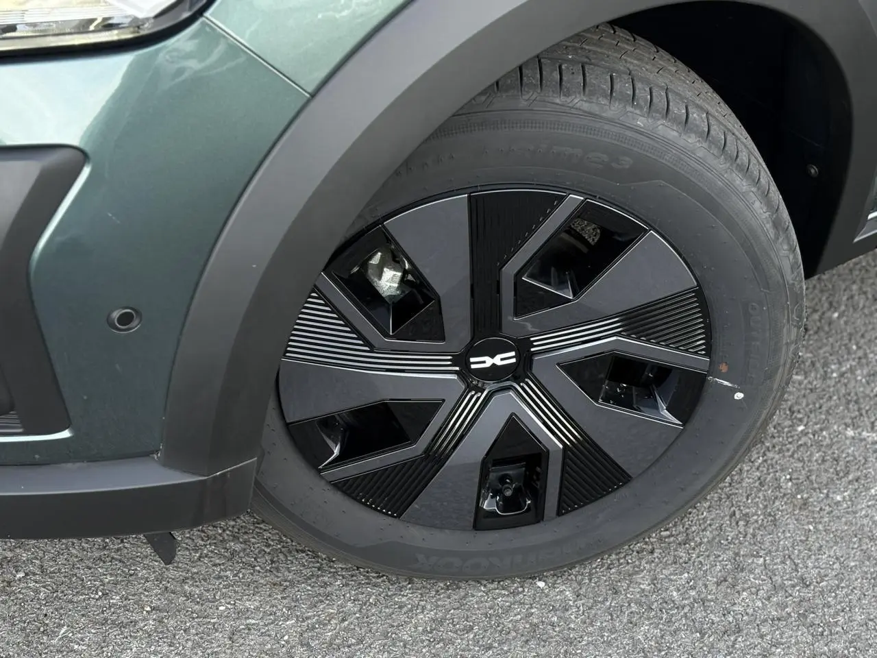 Gros plan sur la roue avant gauche du Dacia Jogger Vert Cèdre 2024 avec jante noire au design géométrique.