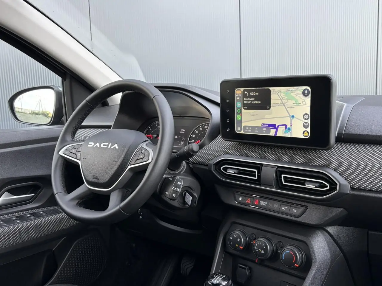 Vue intérieure du tableau de bord et volant Dacia Jogger avec écran tactile GPS et commandes au volant visibles.