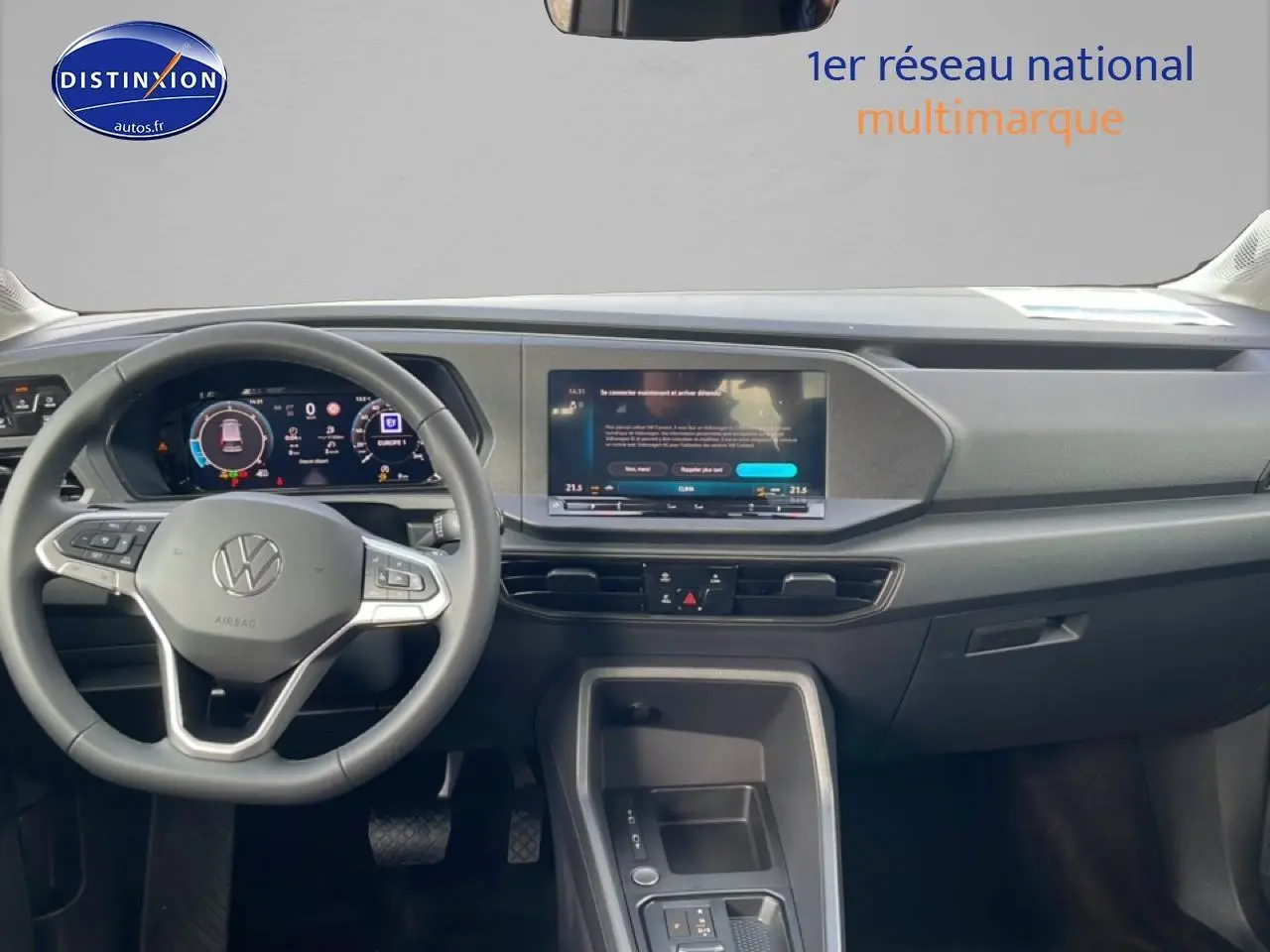Vue intérieure avant du tableau de bord du Volkswagen Caddy 2025 avec écran tactile et volant multifonction gris.