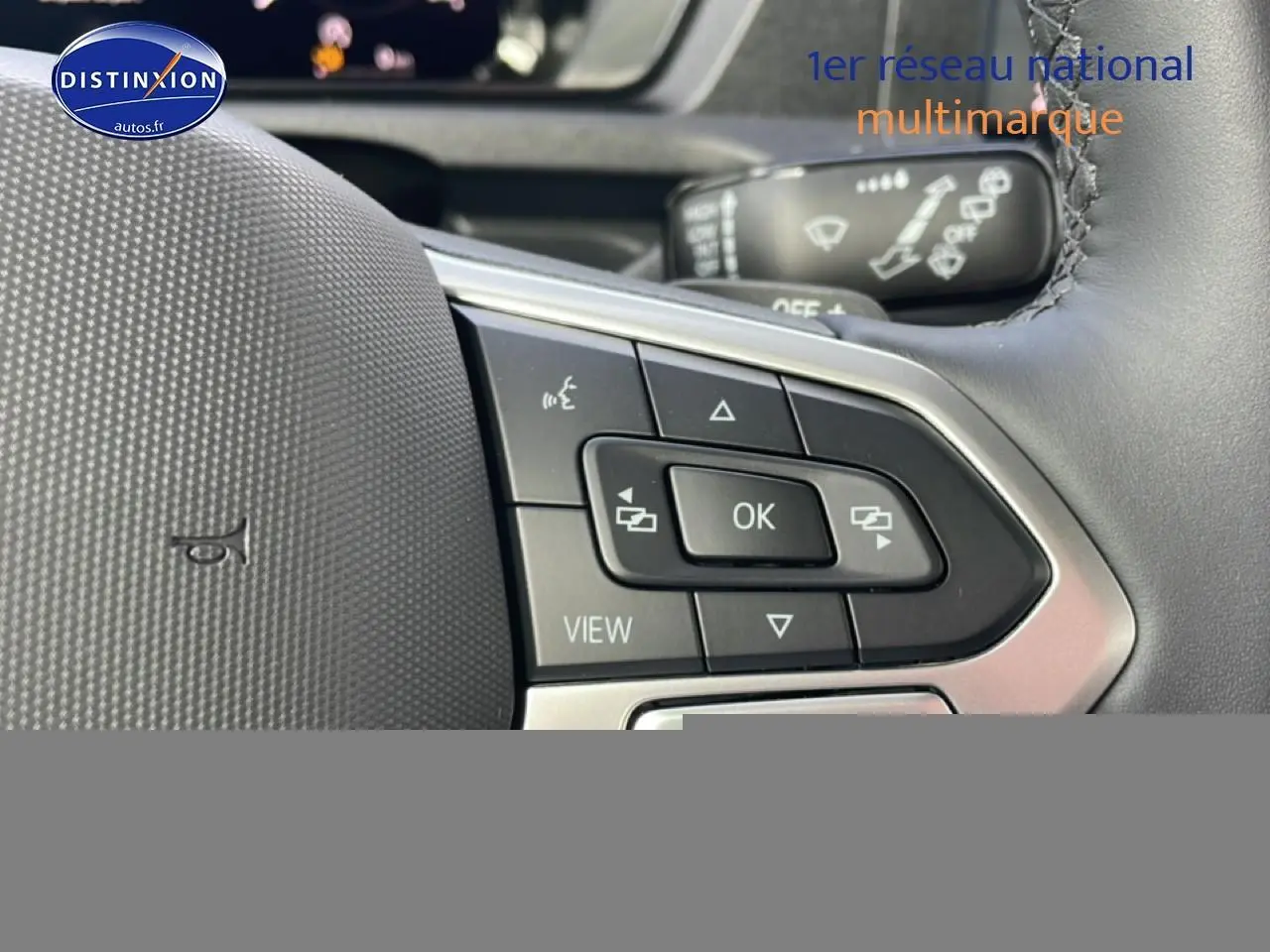 Gros plan sur les commandes au volant cuir multifonction du Volkswagen Caddy 2.0 TDI 122 DSG7, intérieur noir.