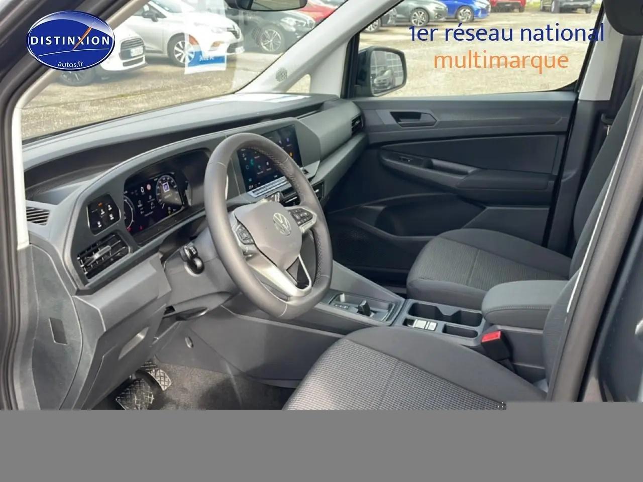 Vue intérieure côté conducteur du Volkswagen Caddy gris indien 2025, avec tableau de bord numérique et volant cuir multifonction.