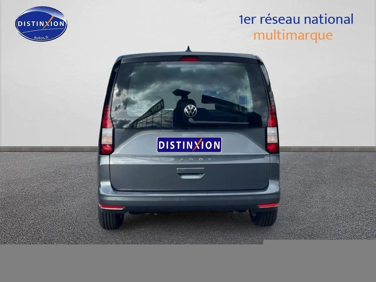 Vue arrière d'un Volkswagen Caddy gris indien 2025 avec vitres teintées et feux verticaux rouges.