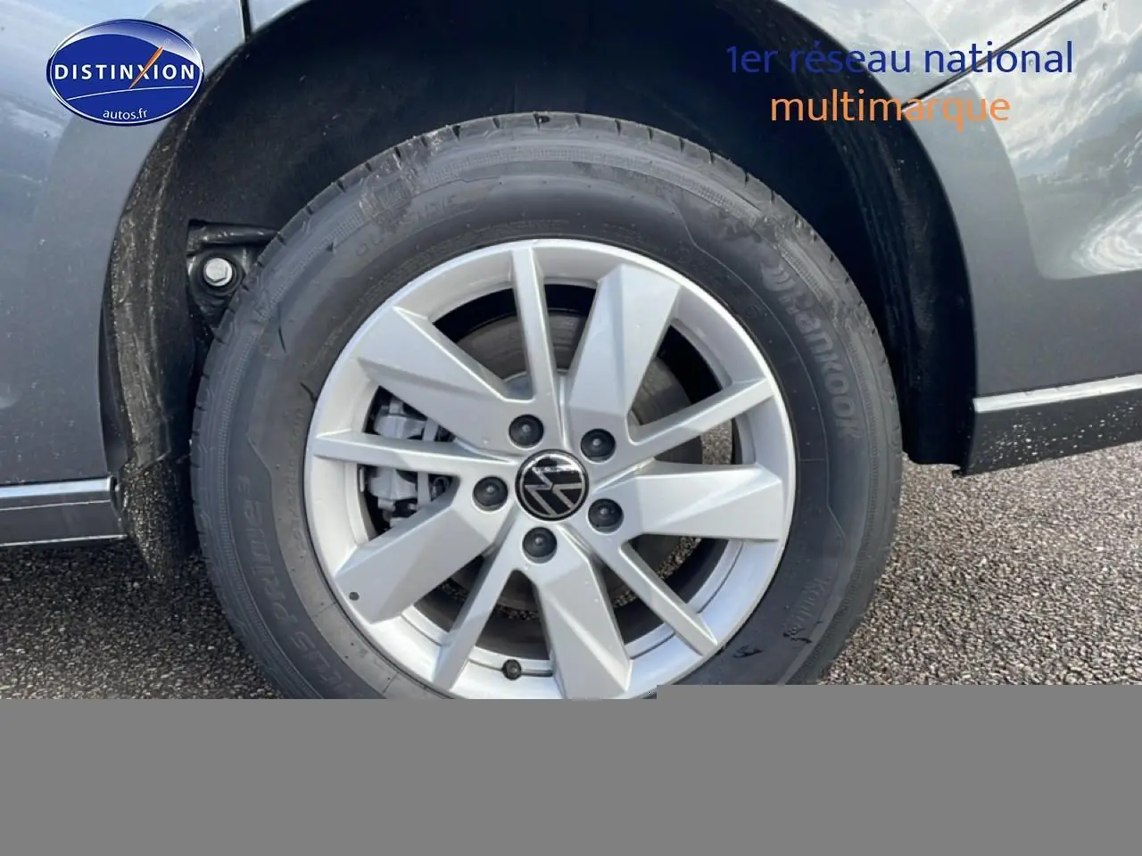 Gros plan sur la roue avant gauche du Volkswagen Caddy gris indien, mettant en valeur la jante alliage et le logo VW.