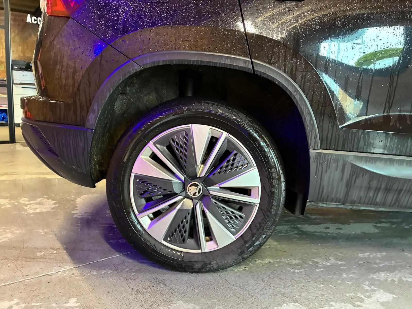 Gros plan sur la roue arrière gauche d’un SKODA KAROQ noir 2023, soulignant la jante au design moderne et le passage de roue.