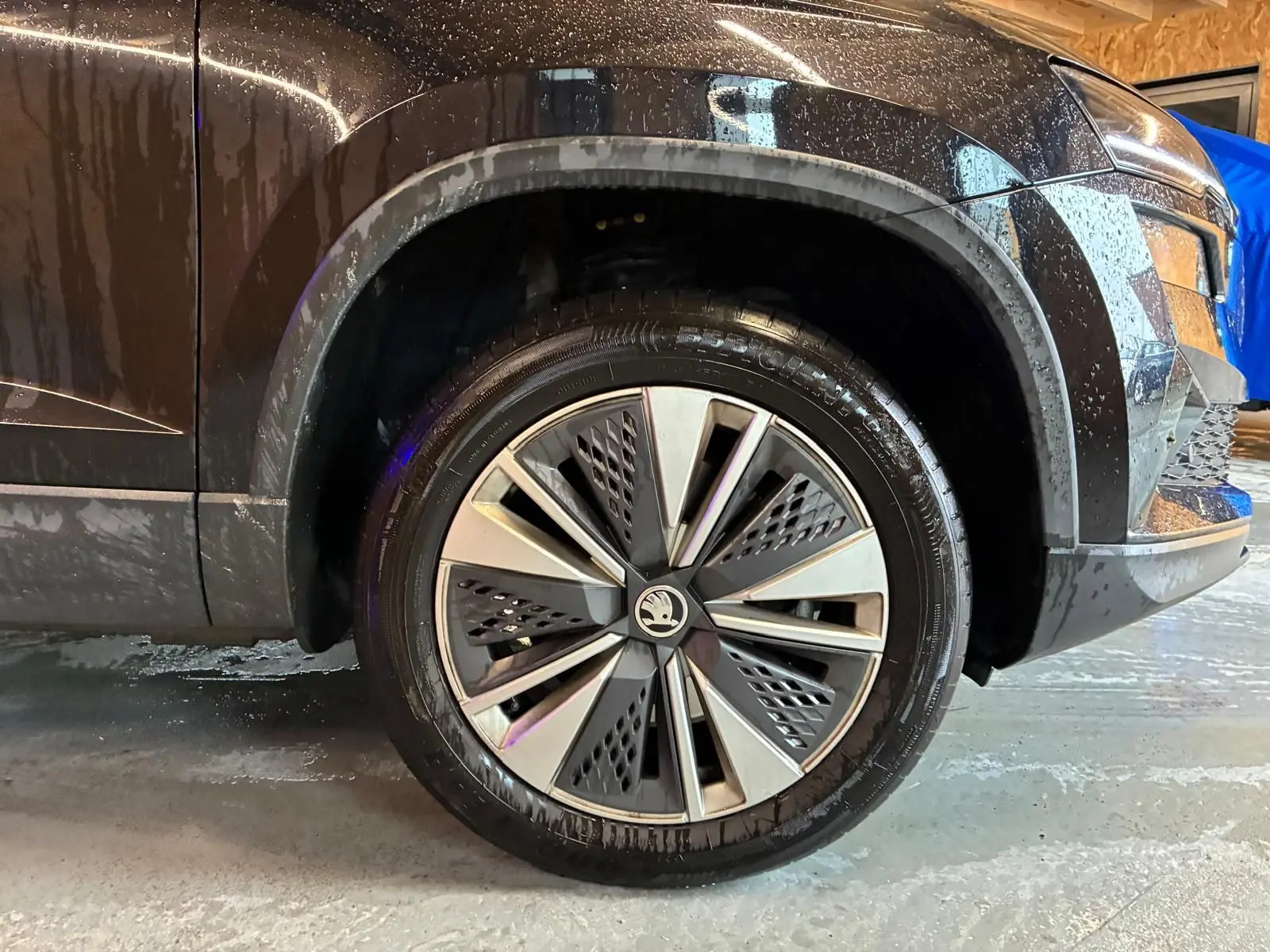 Gros plan sur la roue avant gauche d’un Skoda Karoq noir 2023, mettant en valeur la jante au design moderne bicolore.