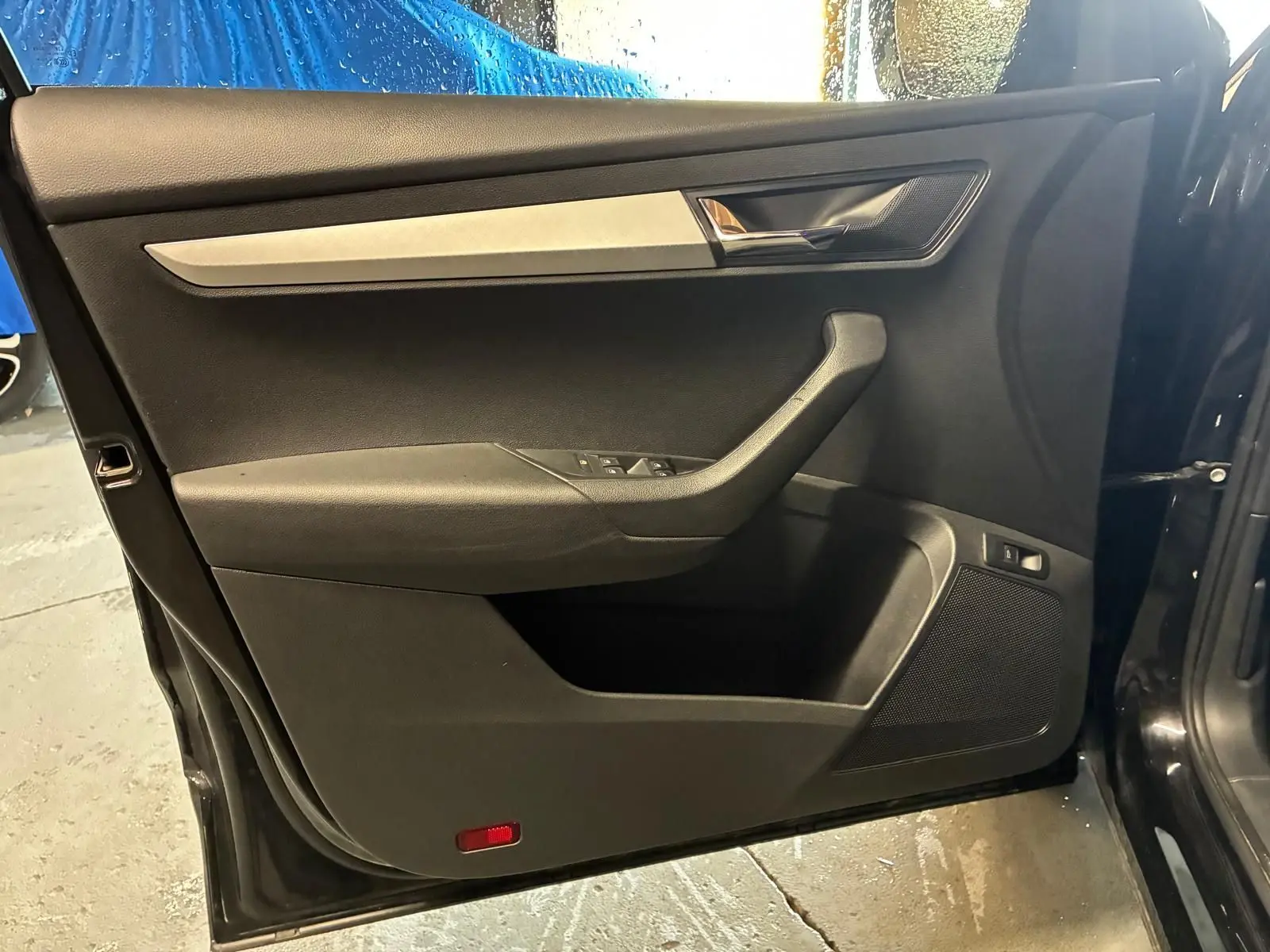 Vue intérieure de la porte avant gauche noire du Skoda Karoq 2023 avec garniture tissu et insert argenté.