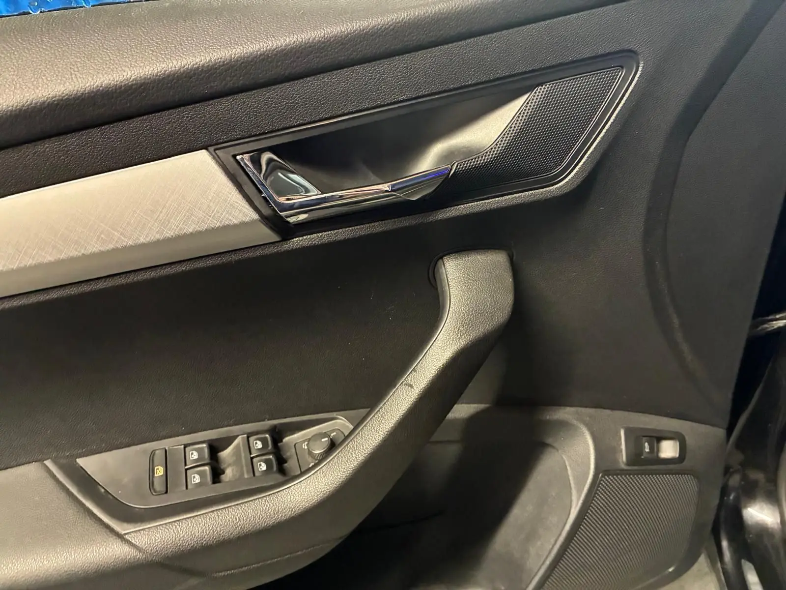 Détail de la porte avant gauche noire du Skoda Karoq 2023 avec commandes de vitres et poignée chromée.