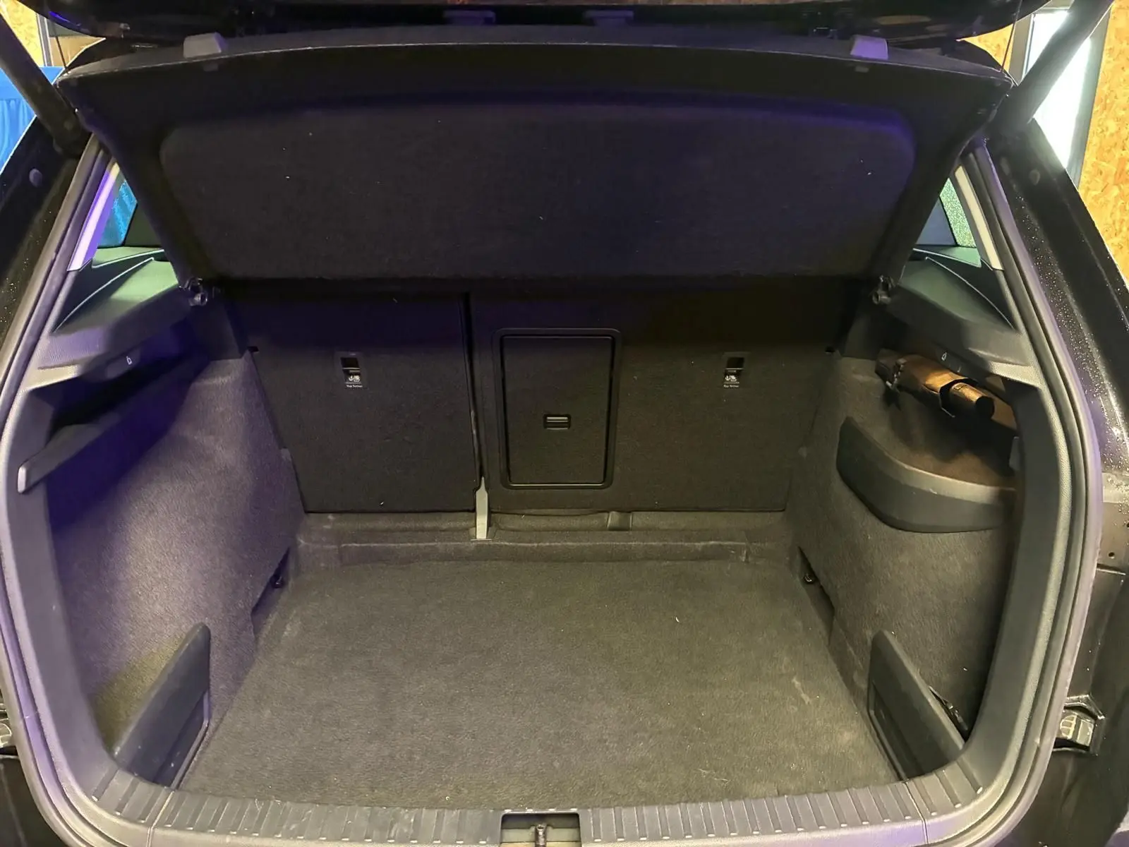 Coffre ouvert vu de l'arrière d'un Skoda Karoq noir 2023, intérieur tissu noir et espace de chargement vide.