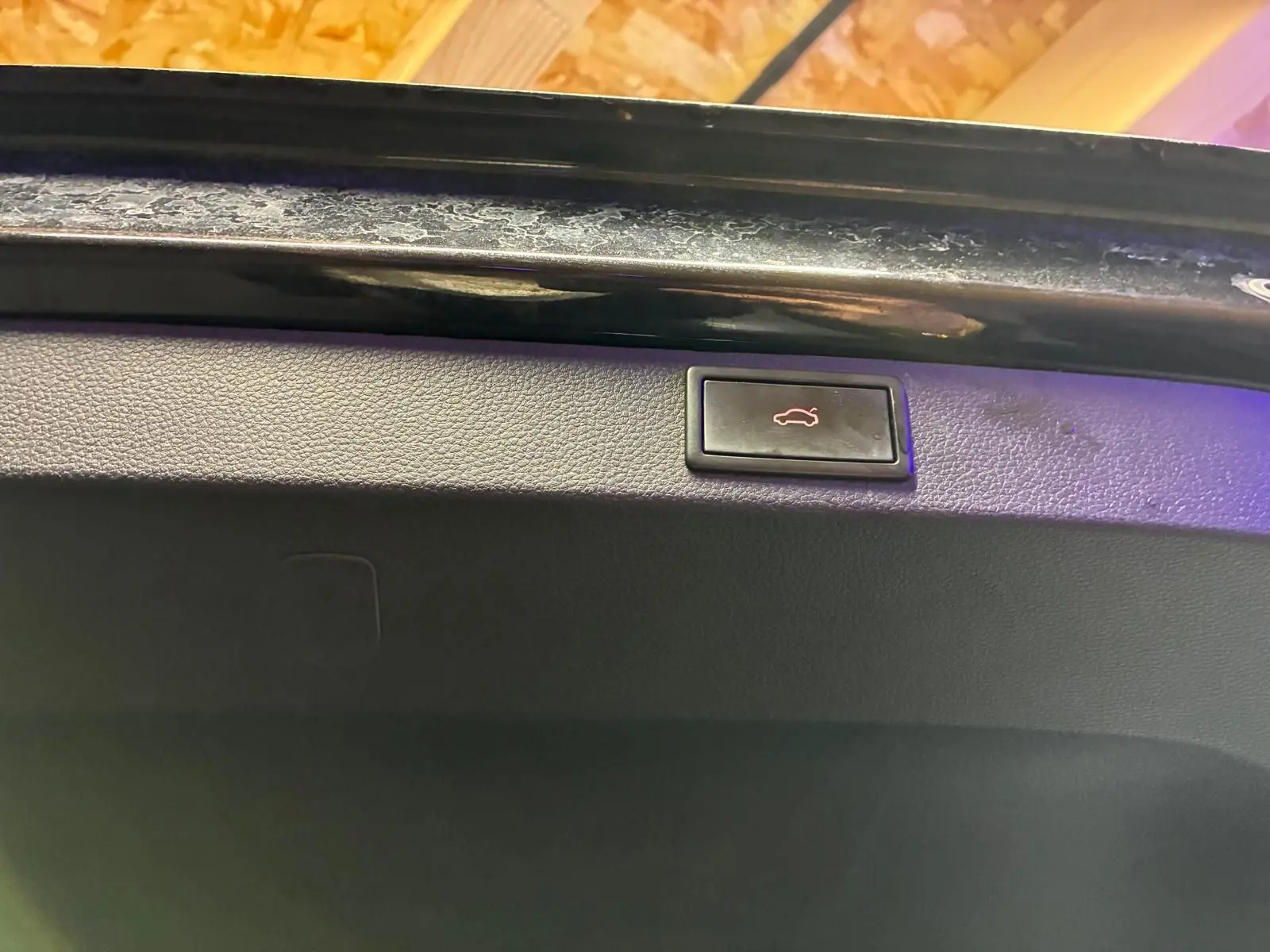 Bouton d'ouverture électrique du coffre sur la partie intérieure de la malle arrière noire d'un Skoda Karoq 2023.