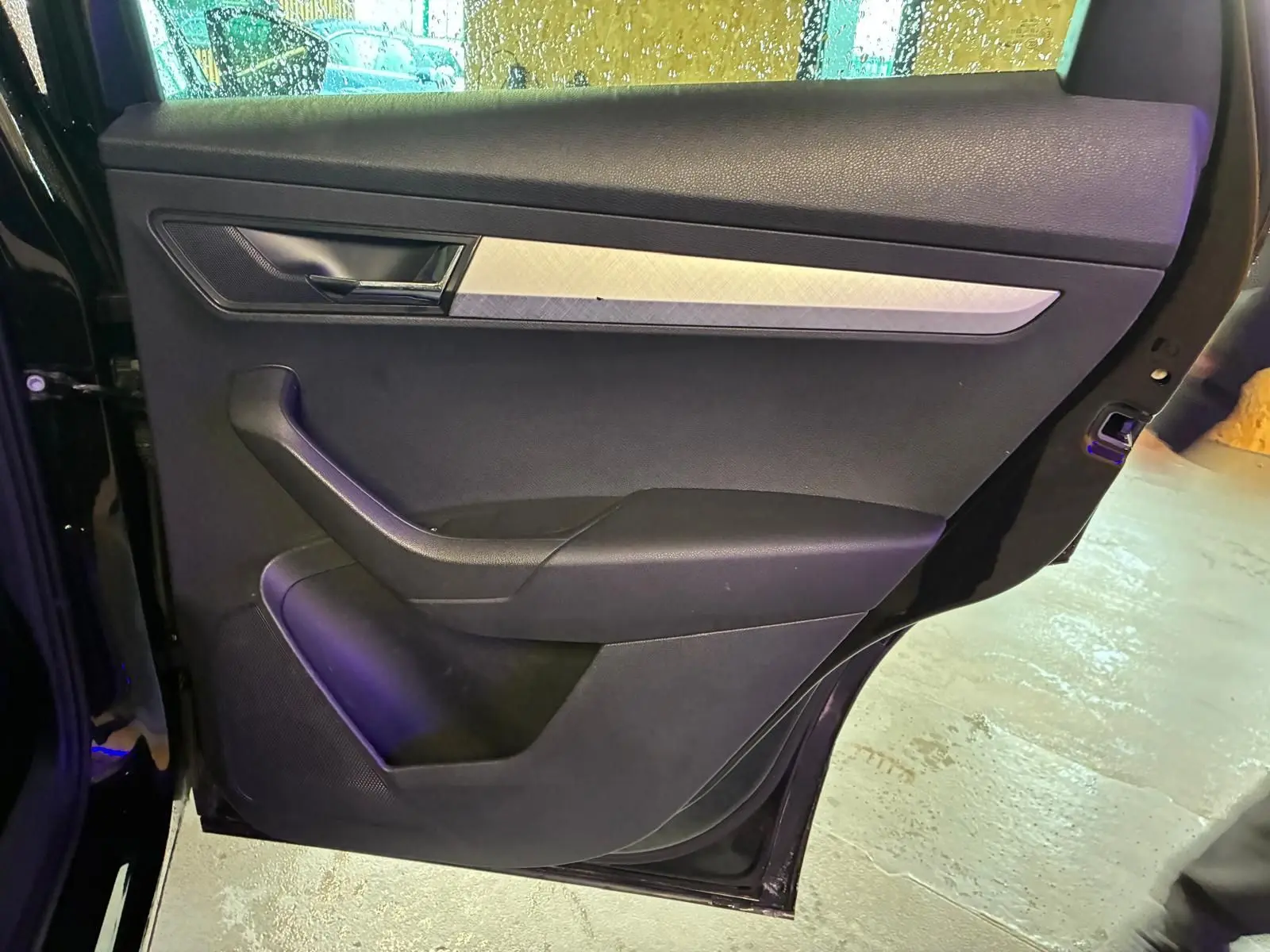 Vue intérieure de la porte arrière gauche noire du Skoda Karoq 2023, avec garniture tissu et insert décoratif argenté.