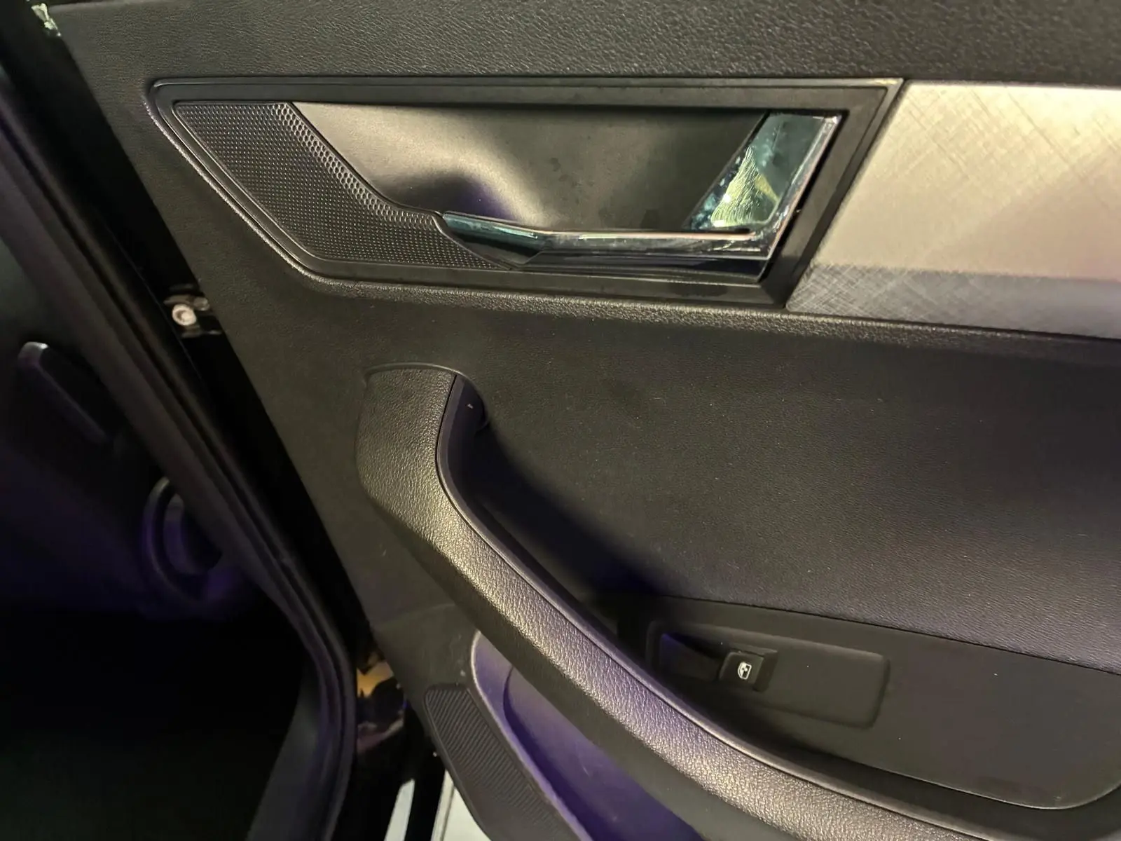 Gros plan sur la poignée intérieure et la commande de vitre côté gauche d'une Skoda Karoq noire 2023.