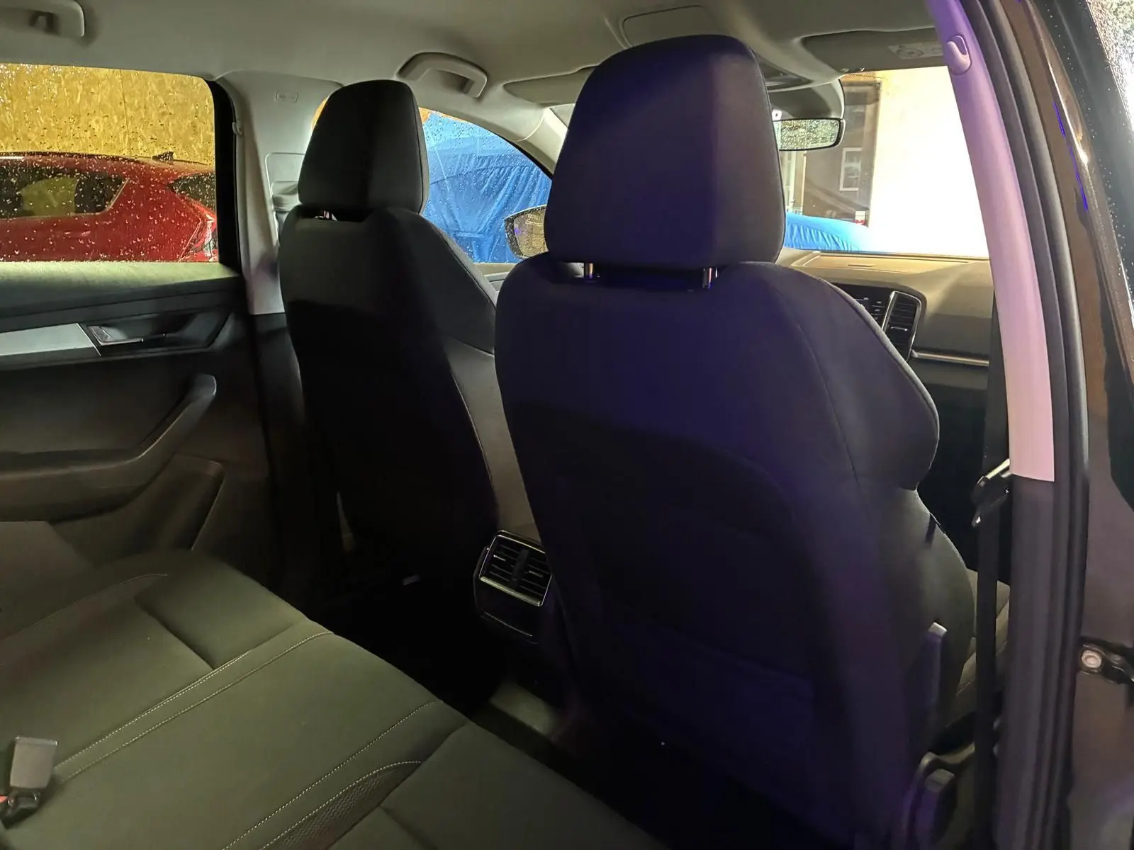 Vue intérieure arrière côté droit du Skoda Karoq noir 2023, mettant en valeur les sièges en tissu noir et les aérateurs arrière.