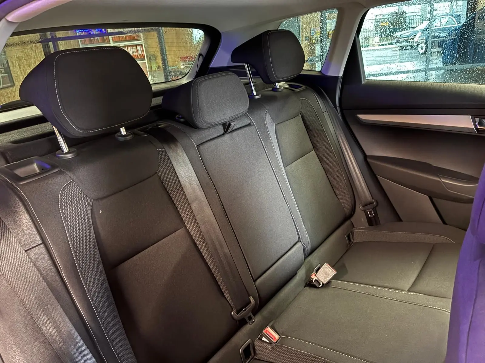 Vue intérieure de la banquette arrière noire en tissu du Skoda Karoq 2023, avec appuie-têtes et ceintures visibles.