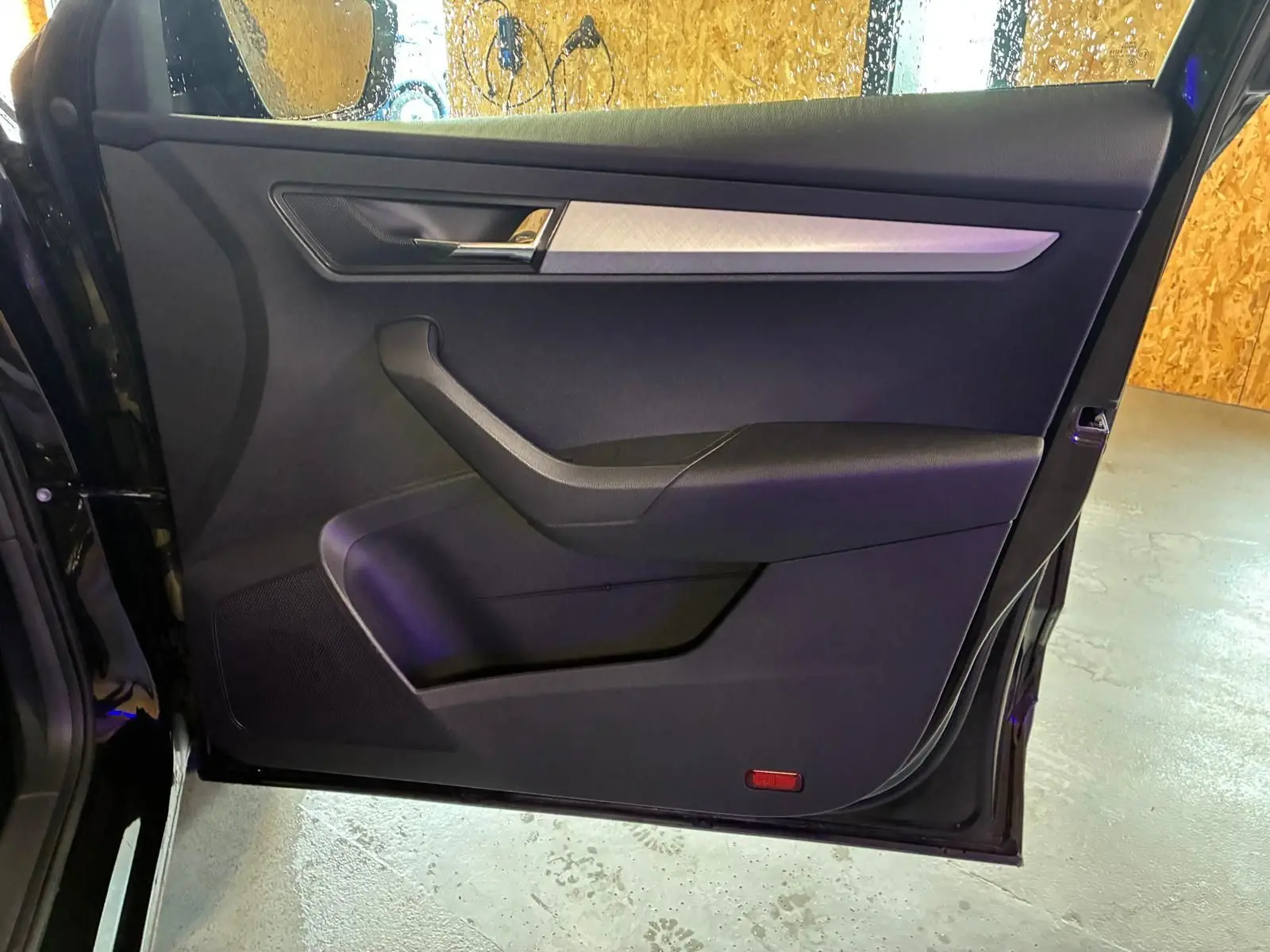 Vue intérieure de la porte avant gauche noire du Skoda Karoq 2023, avec garniture tissu et insert argenté.