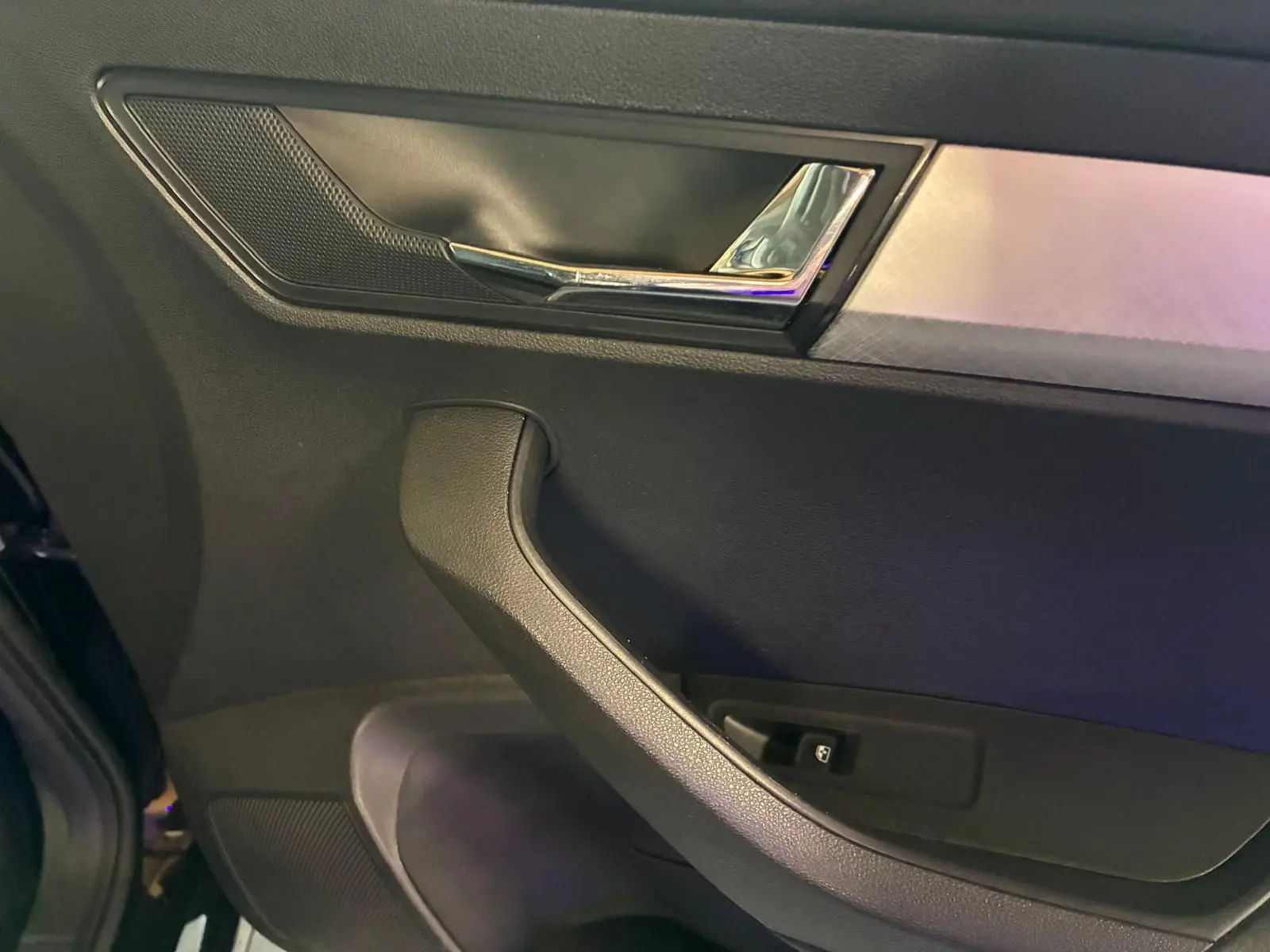 Gros plan sur la porte intérieure côté gauche du Skoda Karoq noir, avec poignée et commande de vitre visible.
