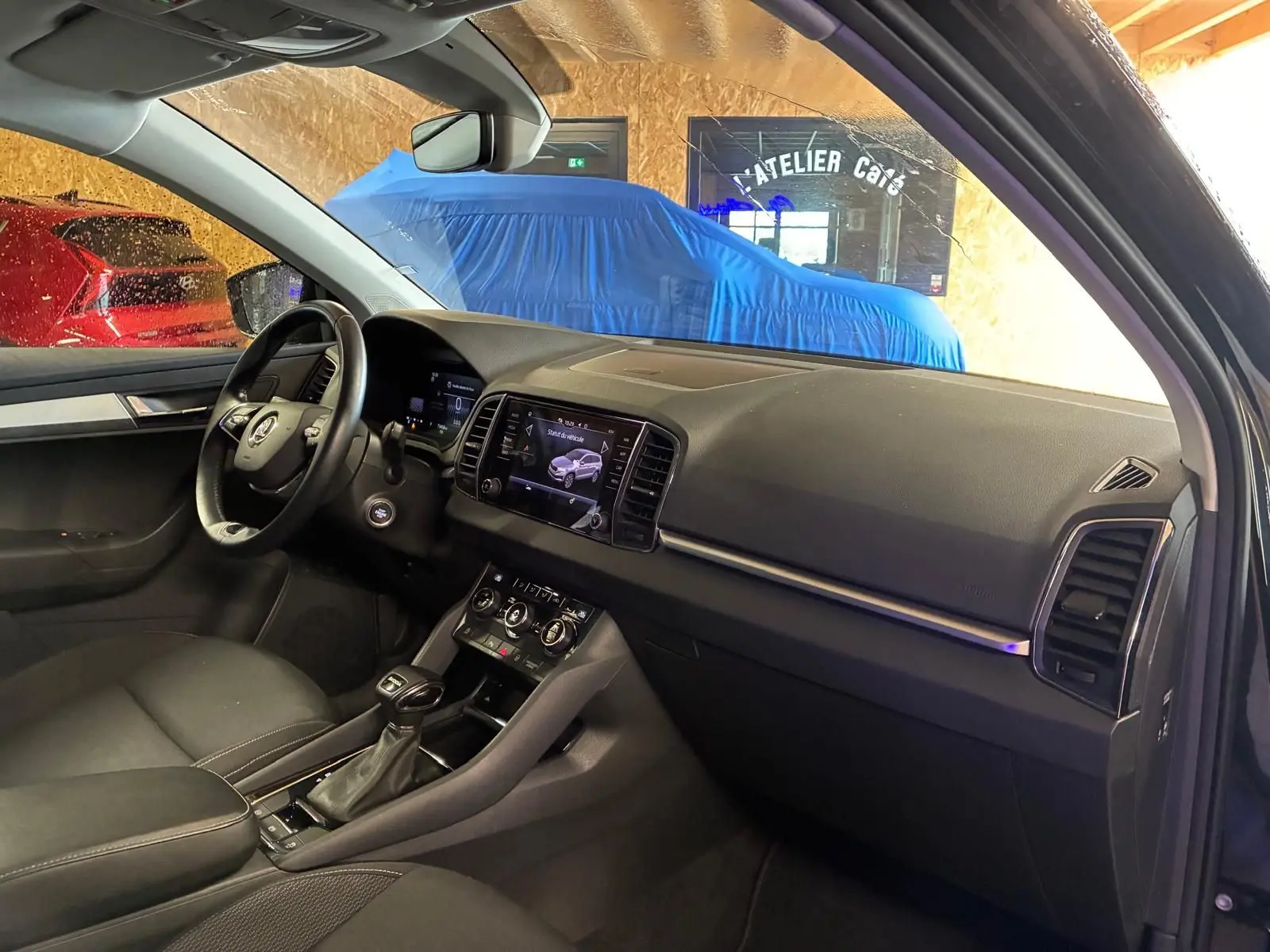 Intérieur noir du Skoda Karoq 2023, vue côté conducteur montrant tableau de bord et console centrale avec écran tactile.