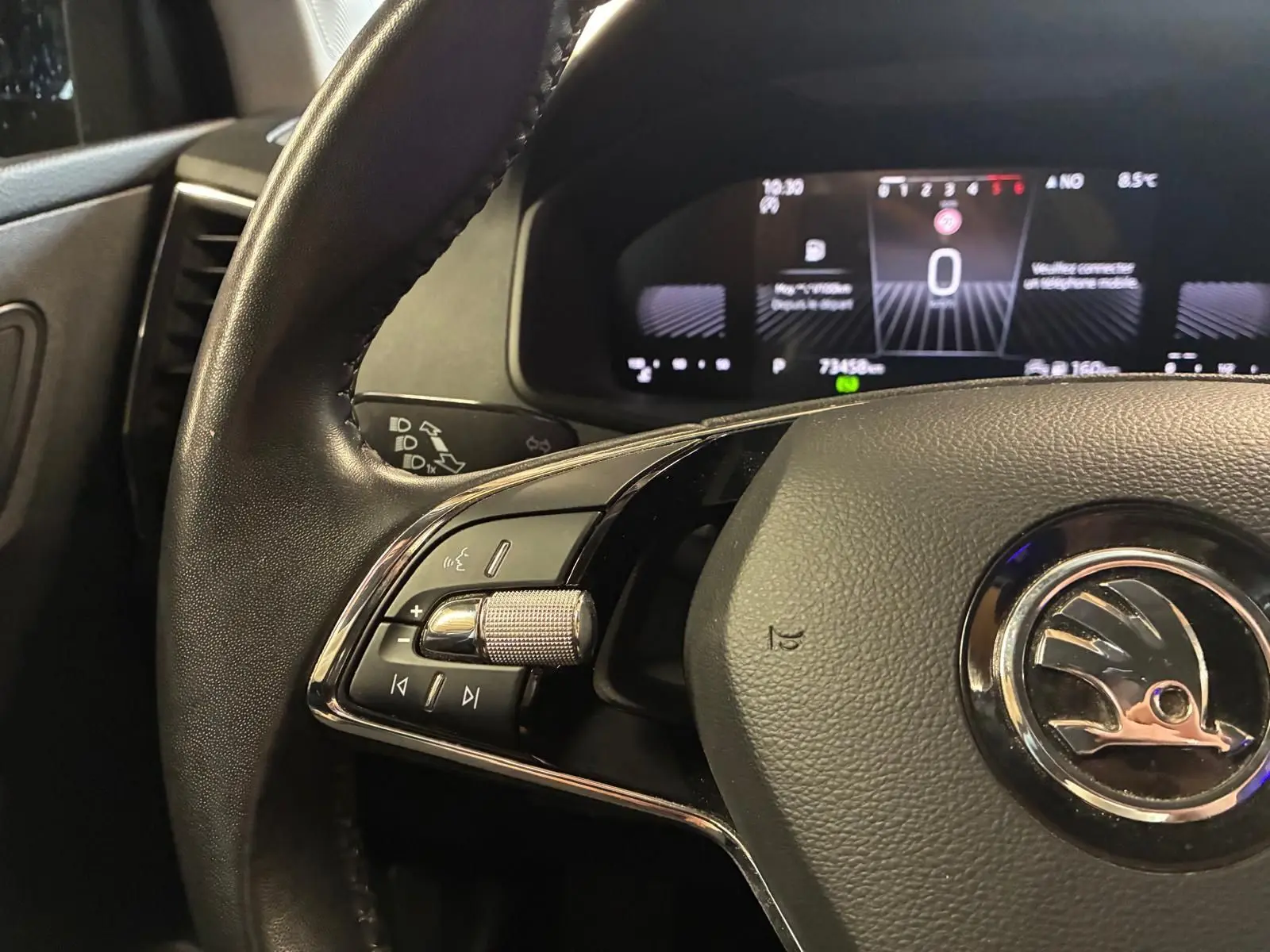 Gros plan sur le volant noir de la Skoda Karoq 2023 avec commandes intégrées et tableau de bord numérique en arrière-plan.
