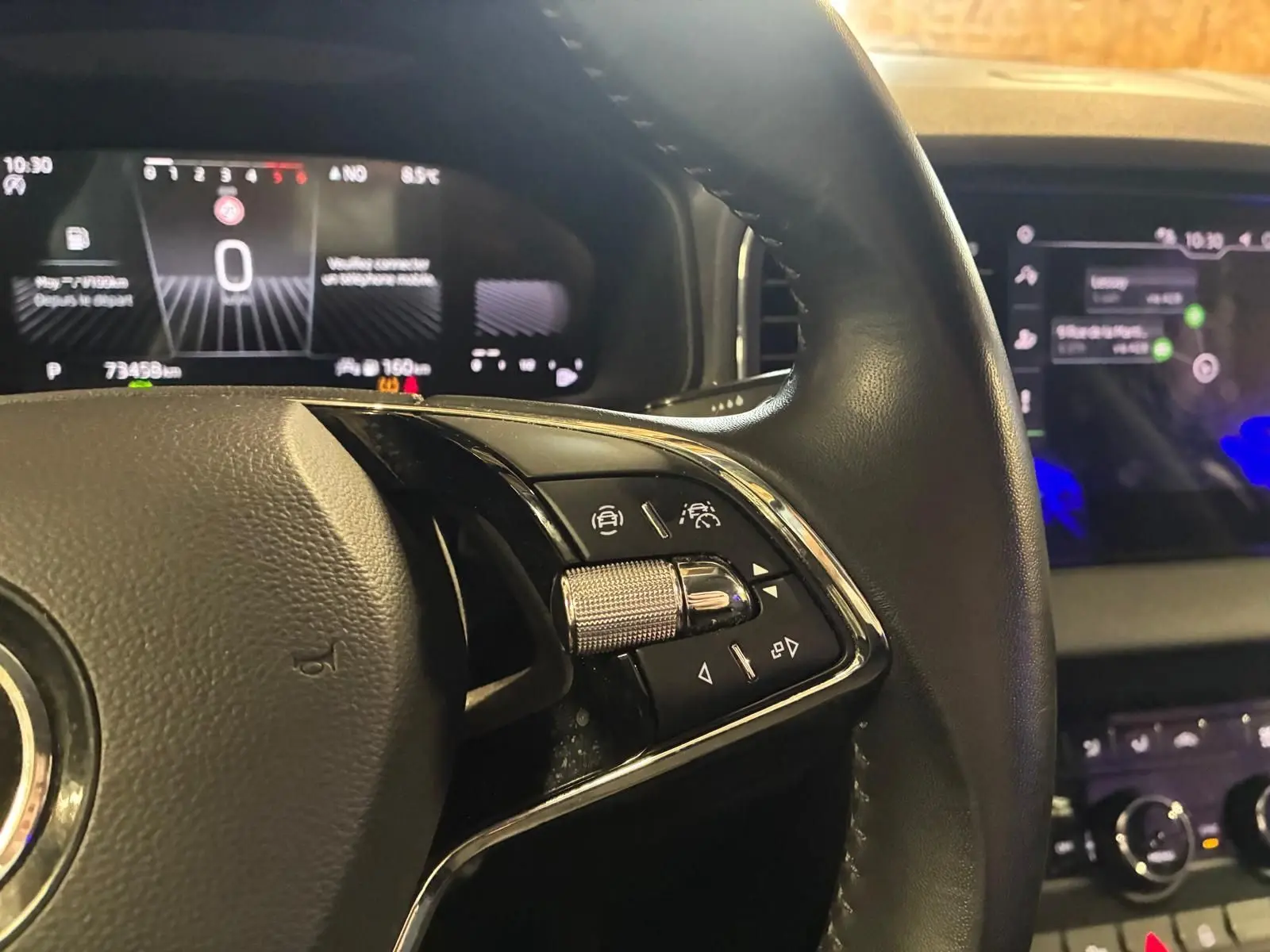 Gros plan sur le volant noir du Skoda Karoq 2023 avec commandes intégrées et tableau de bord numérique en arrière-plan.